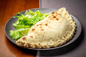 baked calzone. closed type of pizza that is folded in half. Delicious homemade food. author menu