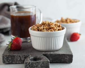 Homemade granola in a white bowl with strawberries and a Cup of coffee. The concept of a healthy Breakfast. Copy space.
