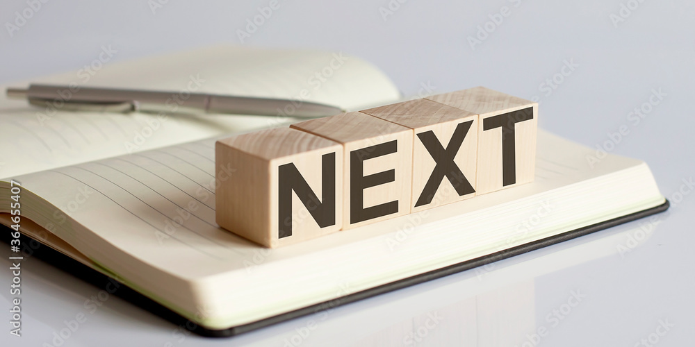 Poster next sign on a wooden block on notebook background