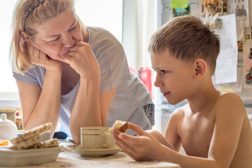 Obraz na płótnie Canvas Grandma and grandson have fun talking, having Breakfast in the kitchen.
