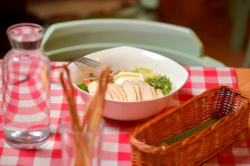 Chicken Caesar salad served in a white bowl. Traditional salad with chicken meat, eggs, tomatoes. Dinner in restaurant.