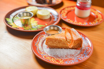 Vanilla cake topping with white powdered sugar. Served on a ceramic plate over light wooden background.