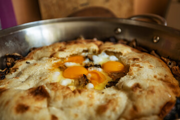 Fresh breakfast fried eggs in pita bread, in a large frying pan, closeup, shallow depth of field, selective focus. Fast breakfast concept