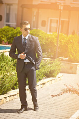 Handsome young businessman walking on city street in the morning going to work in office. Urban lifestyle of young profes