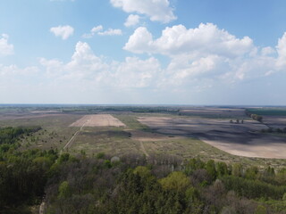 Fototapeta na wymiar Beautiful blue sky over woodland, aerial view. Agricultural land.