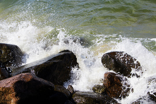 sea waves break on the rocks, a lot of spray. Sunny day.