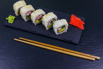 Uramaki sushi rolls with surimi on a black slate