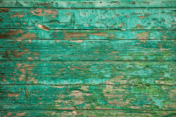 Fototapeta na wymiar Old wooden board with peeling paint. Background of green flaky paint on cracked plank of wood