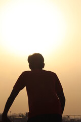   young bettry boy  hiking on top of building in dark shadow over looking san diego at sunset