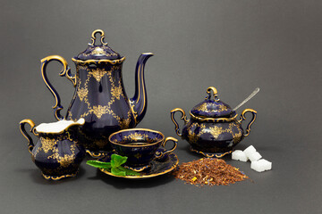 Still life with a cobalt blue vintage porcelain tea set, spoon with sugar cubes, sugar bowl, milk...