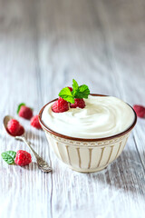 Greek yogurt in a ceramic bowl on a light wooden table.
