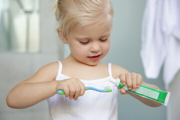 Adorable 3 years old girl brushing her teeth in bathroom.	