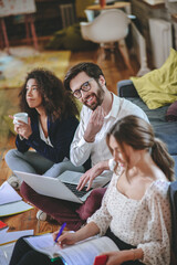 Man with laptop, two girls on both sides sitting on floor