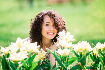Naklejka premium Young attractive woman with curly long hair posing in spring blooming garden, apple trees