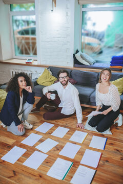 Guy With Coffee, Two Girls On Floor Near Spread Out Documents