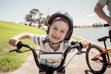 Portrait of cheerful cute kid with helmet riding his bike at the park