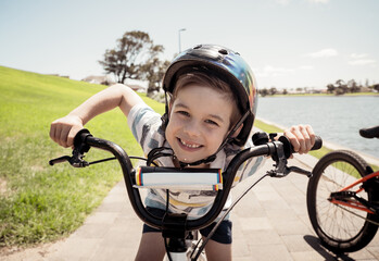 Portrait of cheerful cute kid with helmet riding his bike at the park