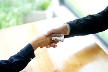 Businessman shake hand with officer and hold the cash