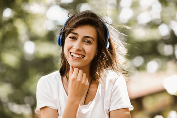Excited girl listening music with headphones in the street with hair moving