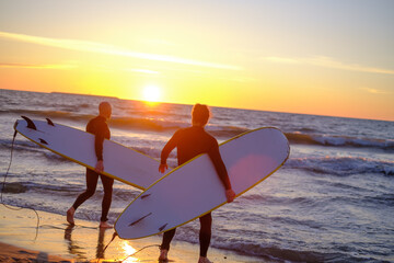 Unrecognizable surfers entering waving sea