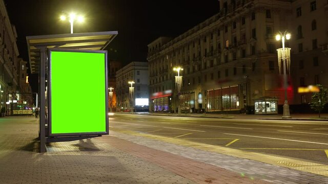 Billboard with a chroma key green screen on n bus stop at night. Time Lapse.