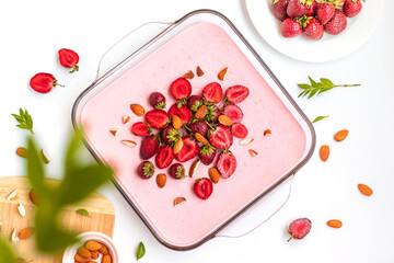 Top view homemade cheesecake with strawberries and raspberries in a glass dish on a white table