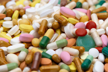 Médicaments de différentes sortes (comprimés, gélules, pilules), tailles et couleurs, entassés en vrac. Concepts de médecine, maladie, traitement, et consommation médicale.