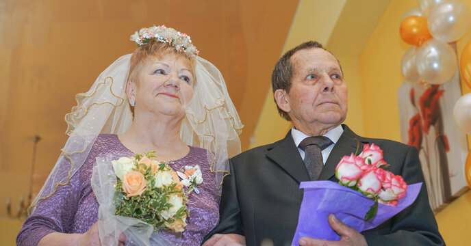 old married couple with flowers bouquets posing for photograph on golden wedding