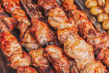 Juicy fresh fried pork meat on skewers on a charcoal grill. Side view of baked ruddy meat on a counter in a street market. Pork kebab cooked at barbecue