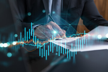 Businessman in suit signs contract. Double exposure with forex graph hologram. Man signing...