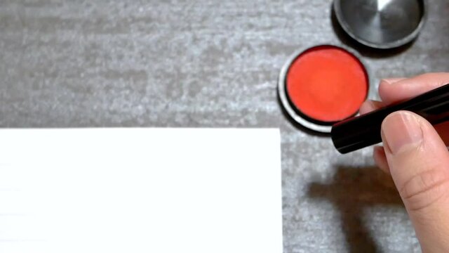 ハンコを持つ。朱肉につけて印鑑を押す様子。