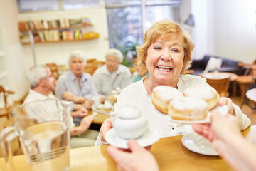 Seniorin holt sich frische Pfannkuchen für die Kaffeerunde im Seniorencafe