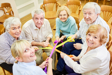 Therapeutin und Senioren machen mit bunten Bändern Übung für den Zusammenhalt