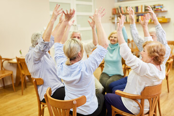 Gruppe Senioren im Altenheim macht Sitzgymnastik oder Bewegungstherapie Übung