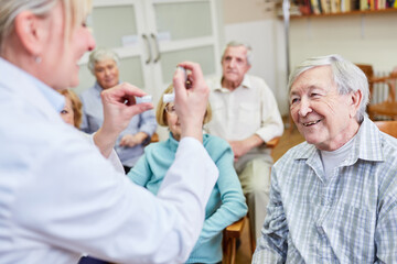 Ärztin mit Dosierinhalator in einer Gesundheitsberatung für Senioren im Altenheim