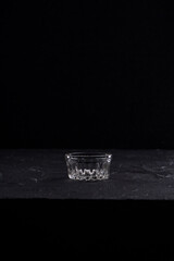 Dish glassware for sauce. Small glass cup on black background.