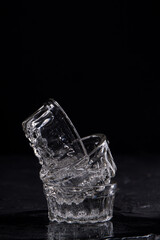 Stack of small glass cups filled with mineral water. Isolated on black background.