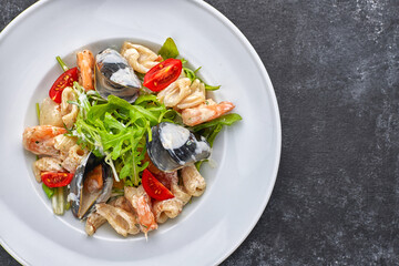 Seafood salad with mussels, squid, shrimp, on a round white plate, on a gray background