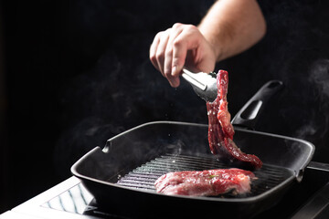 the chef prepares a beef steak in a pan