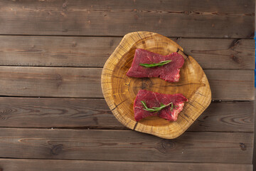 raw beef steaks on wooden board