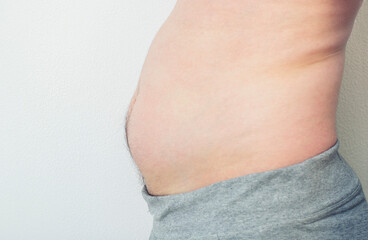 Close up picture of  young man's fatty abdomen on isolated background. Guy wants to pump up the abs on his stomach.