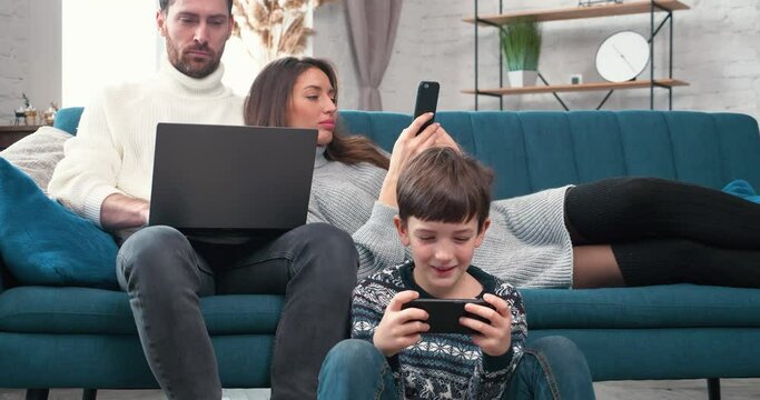 Devices addicted family Parents and kid son use laptops Phone sit on floor at home. Mom, Dad with Child obsessed with Gadgets overuse social media, people internet technology Dependence concept.
