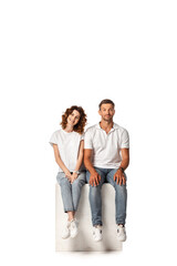 Fototapeta premium cheerful couple smiling and sitting on cube on white