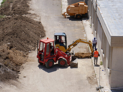 A small excavator performs precision work on a construction site.