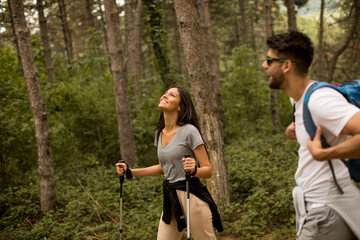 Fototapeta premium Smiling young couple walking with backpacks in the forest