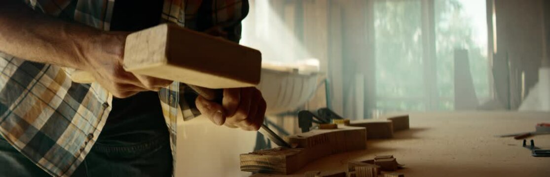 CU Caucasian male shaping canoe paddle with a chisel in his workshop. Boat making hobby, small business owner. Shot on RED Dragon