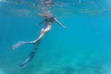 Young woman snorkeling in the sea. Underwater photography of a girl using long fins under the sea.