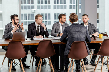 young confident caucasian men gathered to hold business meeting together, to discuss new business ideas and strategies , to share experiences and opinions , isolated in modern office