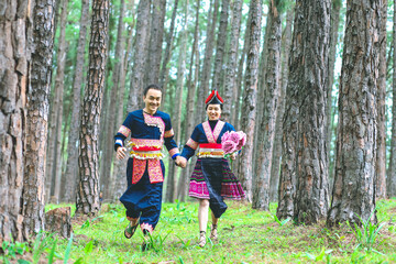 Fototapeta premium Couple hmongs holding hands and running in the pine wood, Man and woman in Hmong clothes