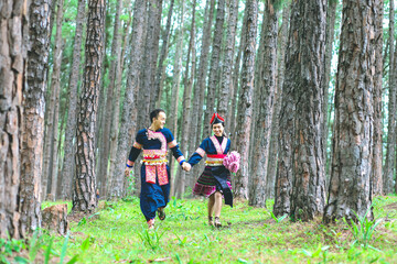 Fototapeta premium Couple hmongs holding hands and running in the pine wood, Man and woman in Hmong clothes